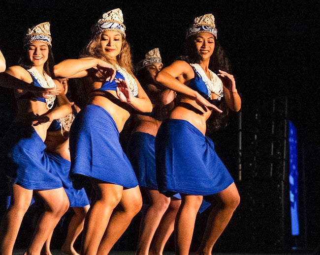 Madi Nguyen-Acosta, pictured with a group, performs a Tahitian dance and wears a blue and white costume 