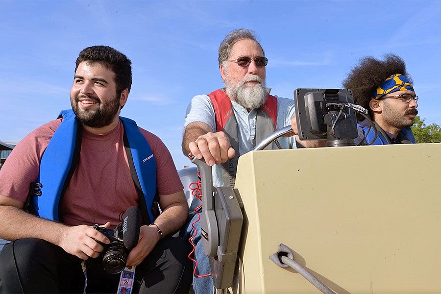 students with cameras ride in a boat