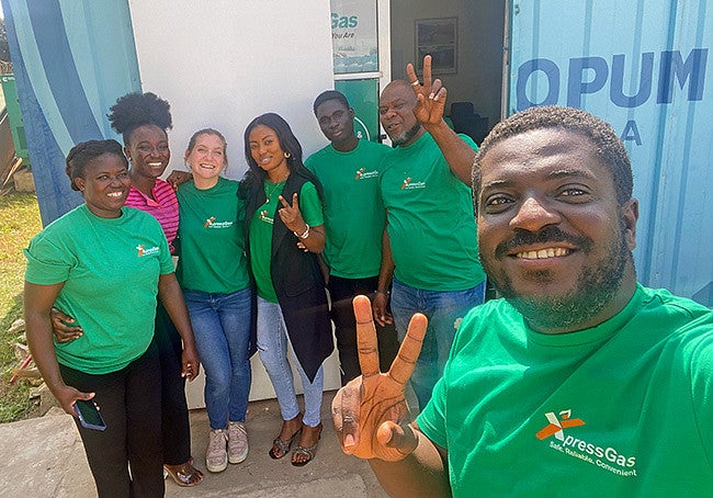A group of people wearing green shirts smile and show peace signs