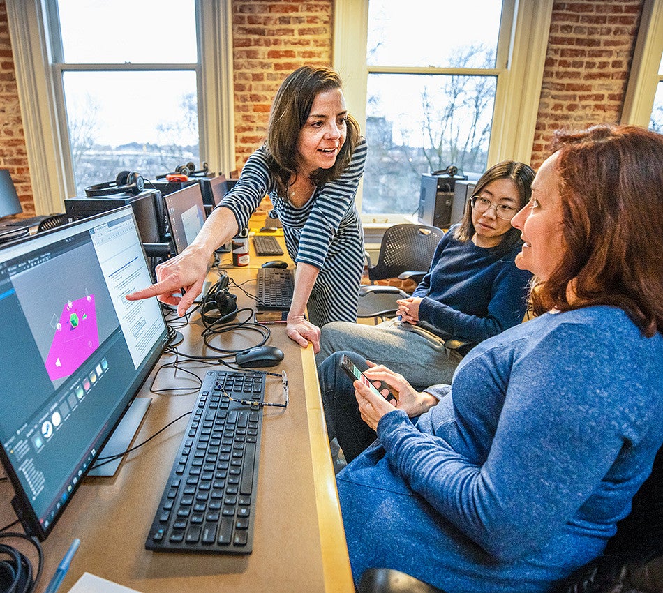Three people discuss images on a computer screen in the Oregon Reality Lab