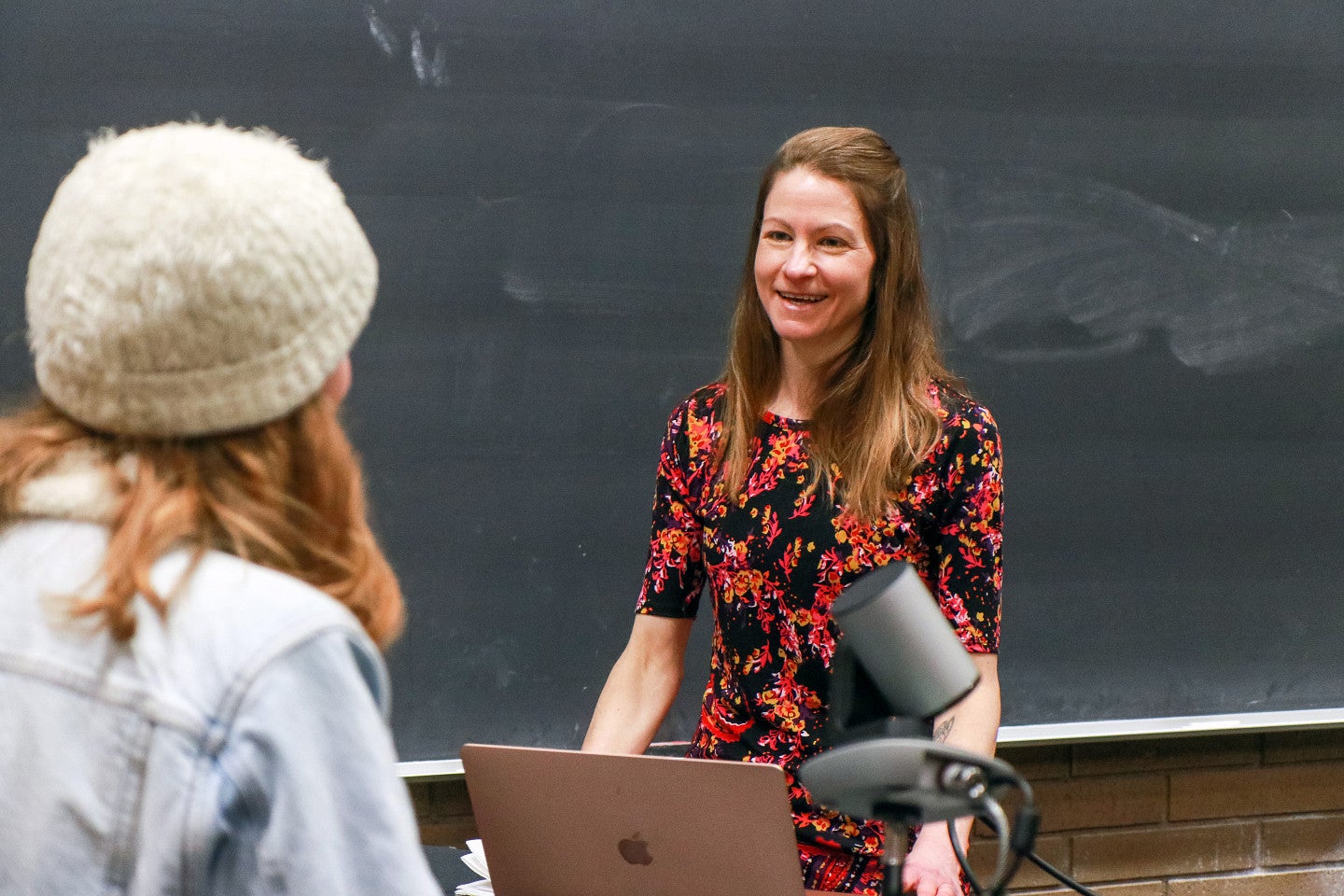 Whitney Phillips speaks to a student in front of a chalkboard