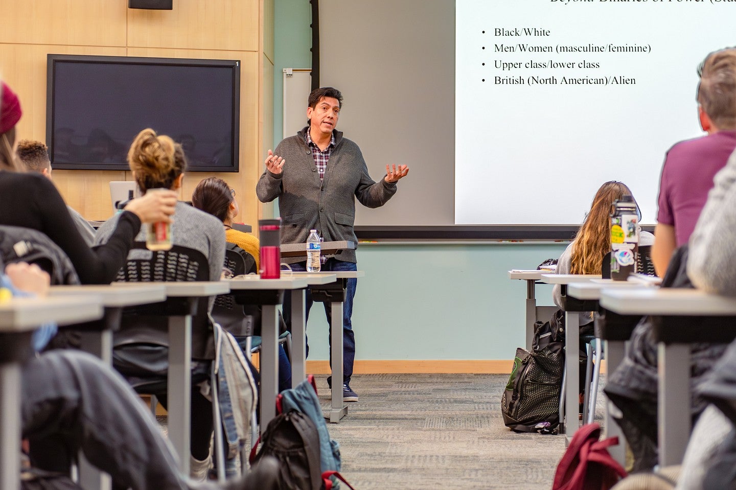 Chris Chavez teaches a class in front of a projector screen