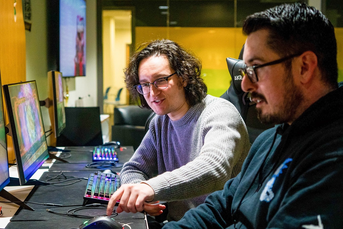 two students in a colorfully lit computer lab