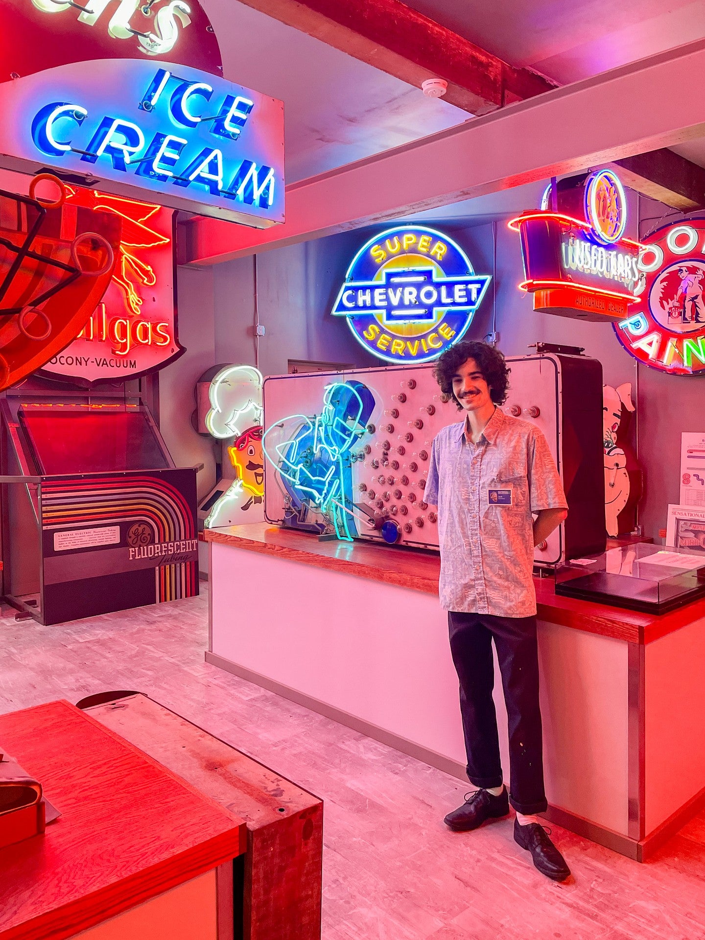 Jack Cochran surrounded by red and blue vintage neon signs