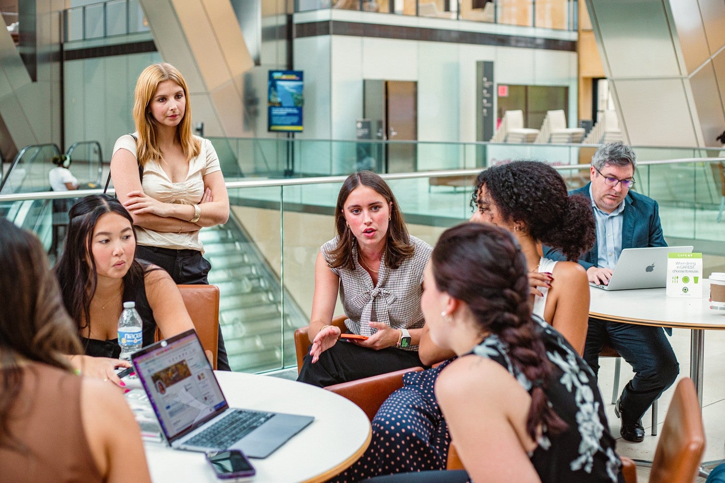 a group of students chat with a staff member in the atrium of the Hearst building in New York City