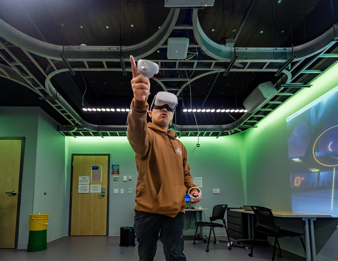 a student wearing a VR headset gestures with an outstretched arm