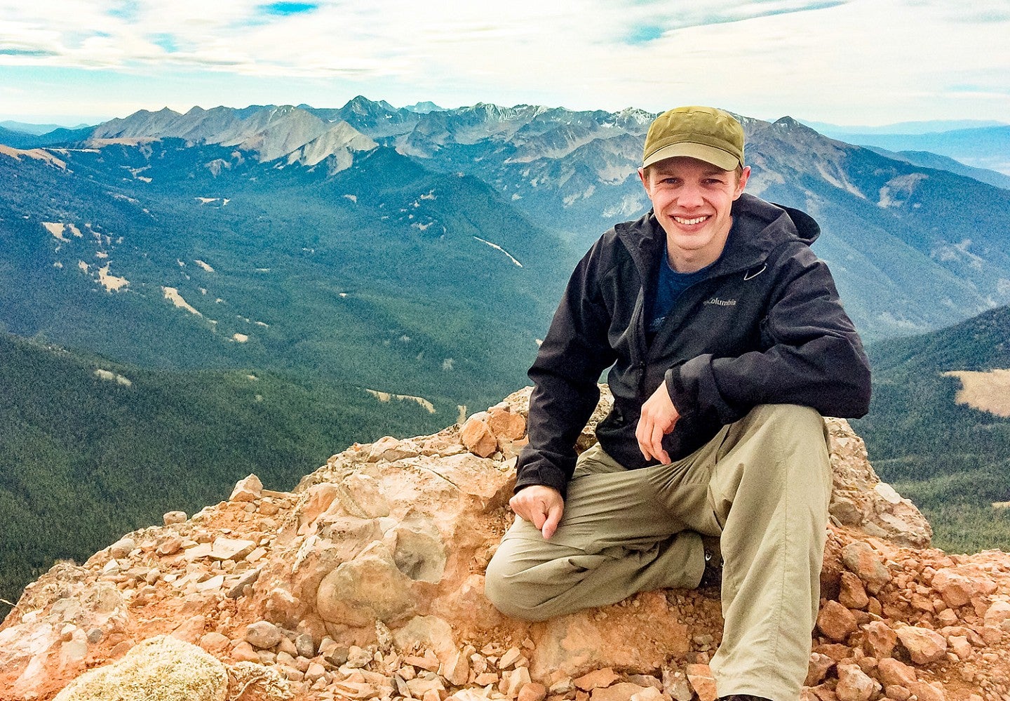 Travis Wilson poses on top of a mountain in Montana