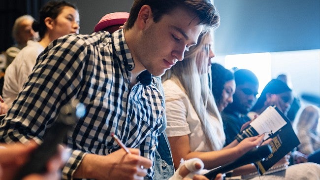 Male student taking notes during course introduction