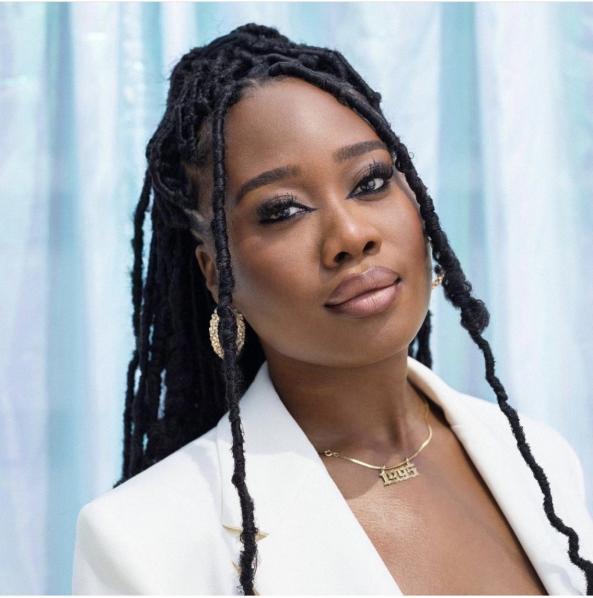 Tylynn Burns strikes a pose in a white suit and gold jewelry.