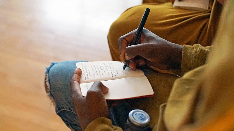 a person's hands writing in a notebook