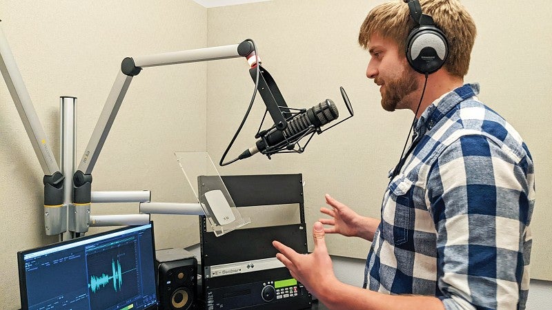 a student records an audio broadcast in a recording studio