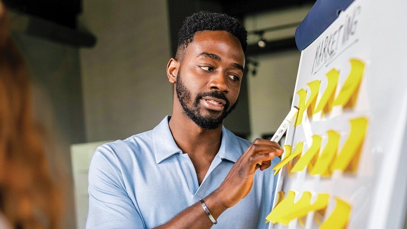 a student points to a board covered in sticky notes