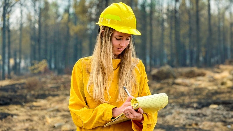 Alexis Weisend reports from the field wearing yellow fire gear 