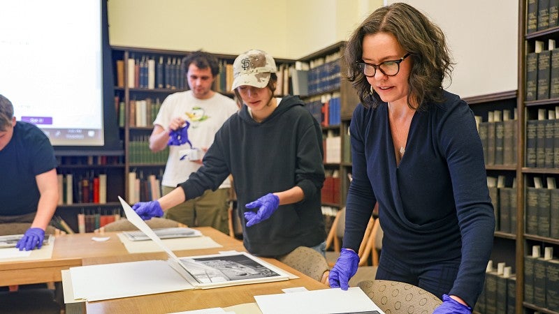 Gretchen Soderlund and students wear purple gloves while handling materials from the UO Libraries' Special Collections