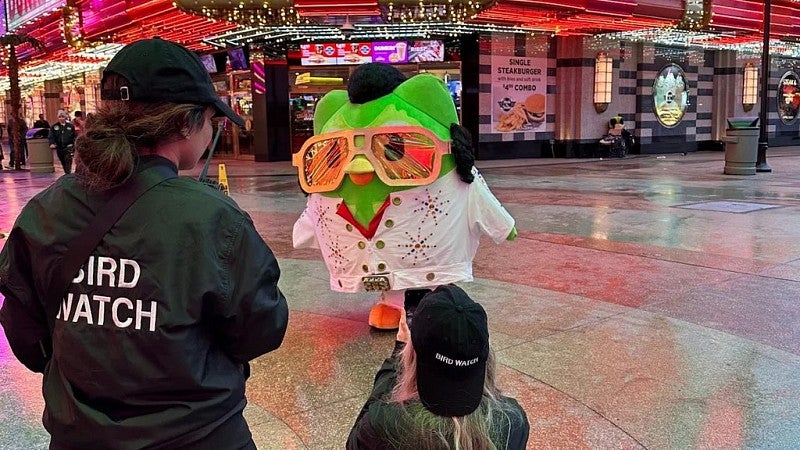 Zaria Parvez stands with the Duolingo owl mascot, who wears an Elvis costume