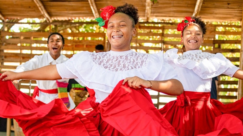 two young dancers wearing traditional Colombian costumes of white blouses and vibrant red skirts