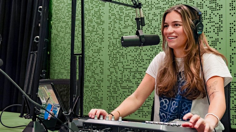 Julia Boboc records a podcast in the SOJC podcast studio lit in green