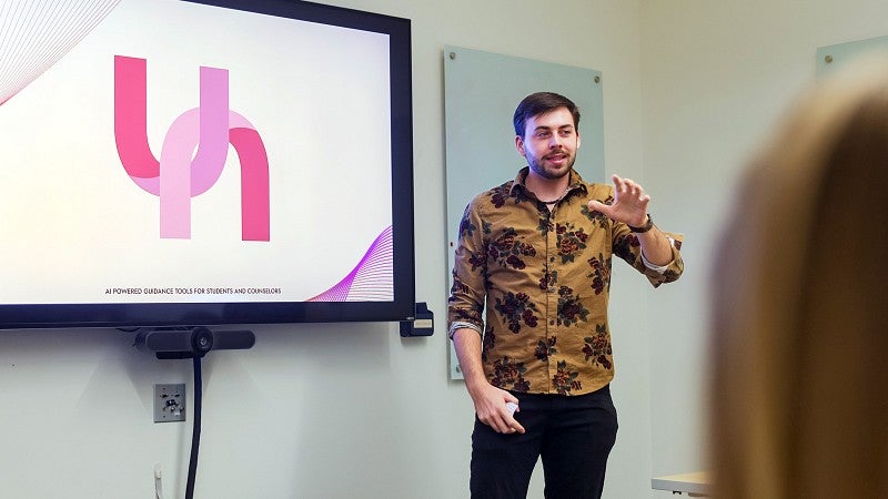 a public relations student presents a client case study on a large display screen