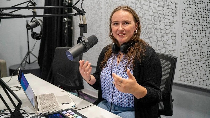 Erin Morrison speaks into a microphone in the SOJC podcast studio