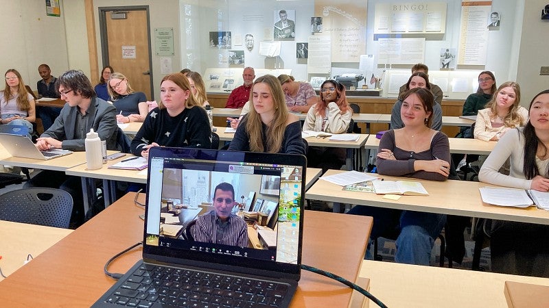 students in a classroom looking at a digital display screen 