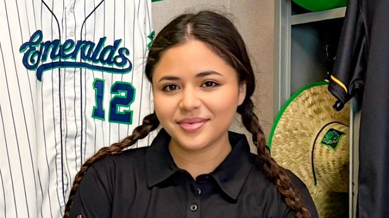 portrait of Sarah Ortiz taken in the Eugene Emeralds locker room where she is surrounded by Emeralds' gear
