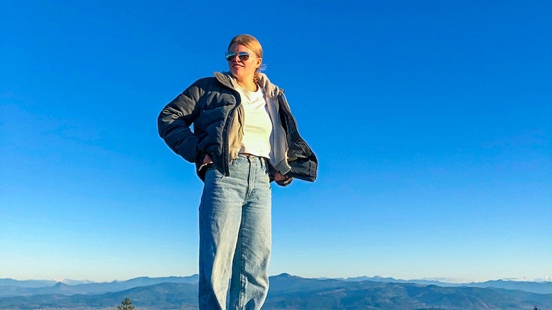 Annika Nagat standing on a rock with a vibrant blue sky covering most of the background