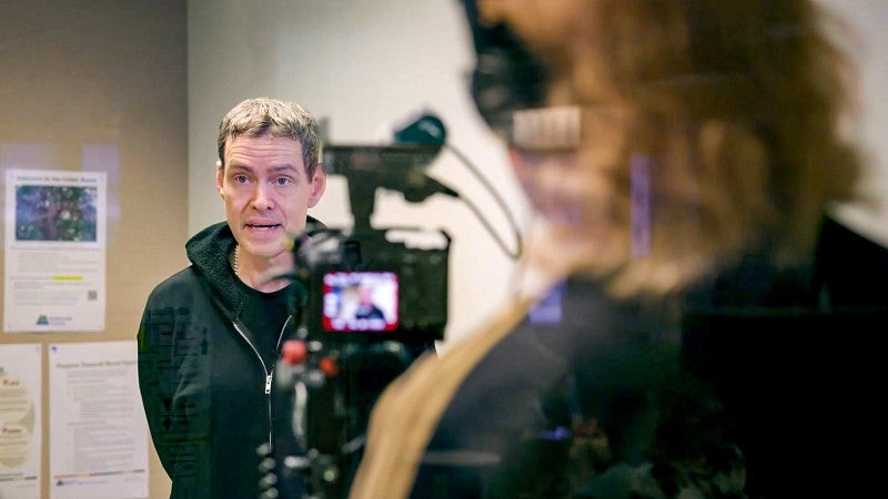 Kelly Clendenon is interviewed on camera with the camera and videographer seen in the foreground