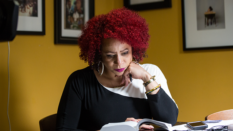 Nikole Hannah-Jones sits at a desk reading a book.