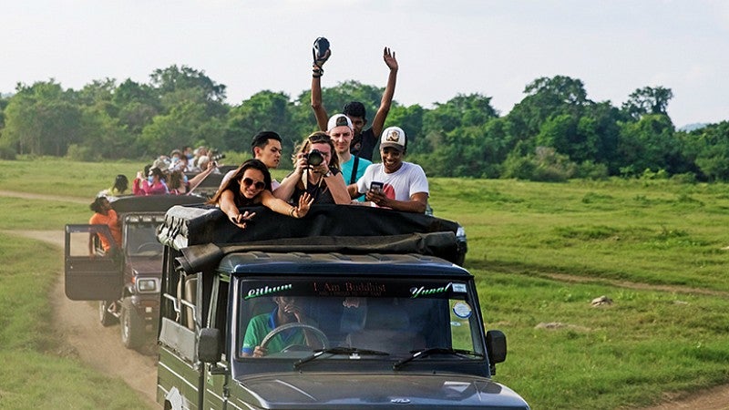 Students riding in Jeeps taking photos. People riding in Jeeps taking photos.