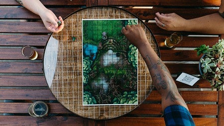 Three people play a board game with beers nearby