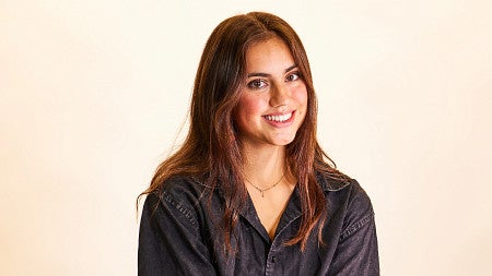 Chloe Montague sits on a stool wearing a black oversized shirt