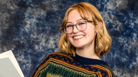 Grace Newlin poses for a portrait holding a book