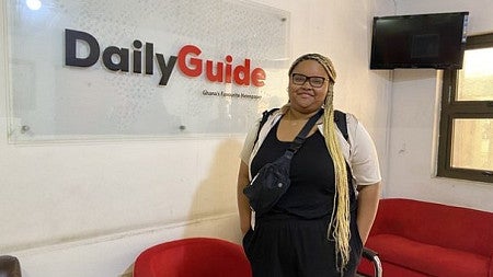 Kiasia Baggenstos stands in front of the Ghana Daily Guide sign