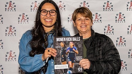 Jackie Gutierrez and another person hold a copy of Women Kick Balls magazine