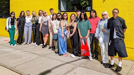 a group of SOJC advertising students poses in front of a bright yellow building