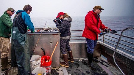 Denise Silfee photographs fishermen while on a boat in Alaska