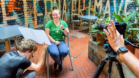 Students set up a portrait location using a test model wearing a green UO tee shirt