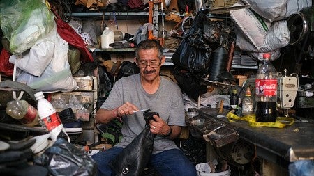 a man brushes a leather boot surrounded by cobbler's materials