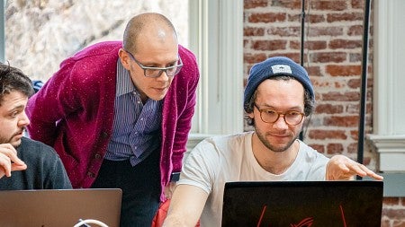Maxwell Foxman leans over to review a student's laptop screen