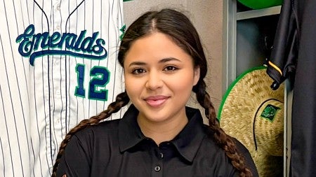 portrait of Sarah Ortiz taken in the Eugene Emeralds locker room where she is surrounded by Emeralds' gear