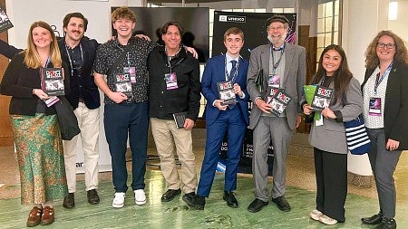 a group of University of Oregon students and professors pose while holding books