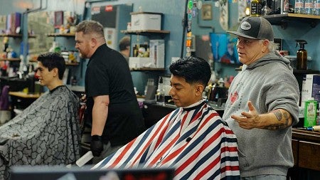 a scene from a barbershop with two people getting haircuts