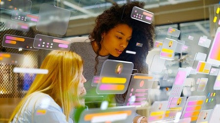 stock photo showing two wome studying digitally rendered screens