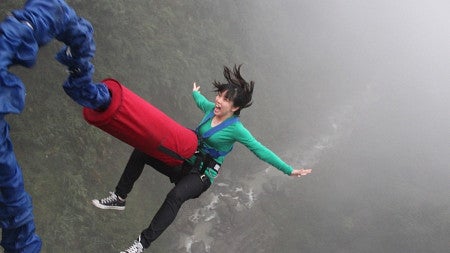 Person bungie jumping over water.