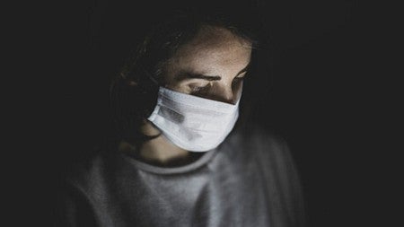 A person who is wearing a face mask is illuminated by a phone screen (by engin akyurt). 
