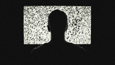 A person in front of fuzzy screen.