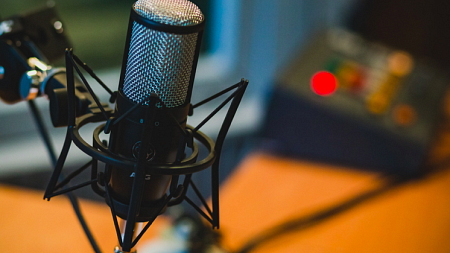 Podcast microphone in front of audio mixer.