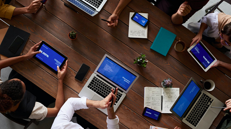 Coworkers sit around a table discussing online content.