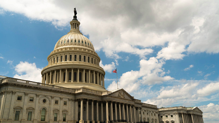 A photograph of the US capitol building under a blue sky with white clouds above.