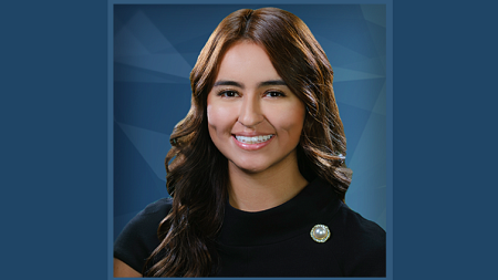 Manuela Baez, wearing a black blouse, smiles at the camera.